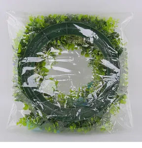 Detail view of a green leaf artificial wreath with blue ribbons inside clear packaging