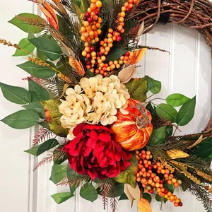 Vue détaillée d'une couronne d'automne avec fleurs rouges et citrouilles déco