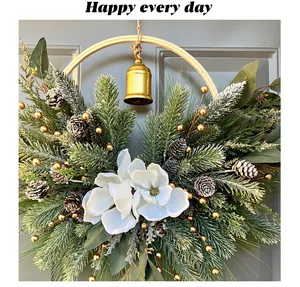 Close-up of a Christmas pine needle wreath with white magnolia and golden bell ornament