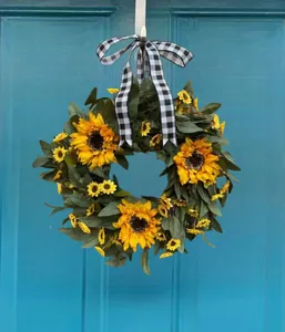 Detail van zonnebloemkrans met groene bladeren en een geruite strik voor de voordeur