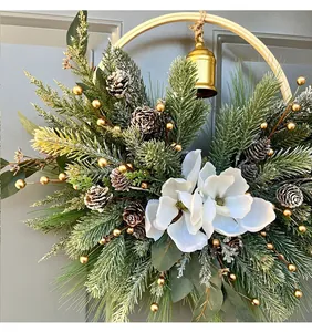 Close-up detail of a festive Christmas wreath with white magnolias, pine cones, and a golden bell
