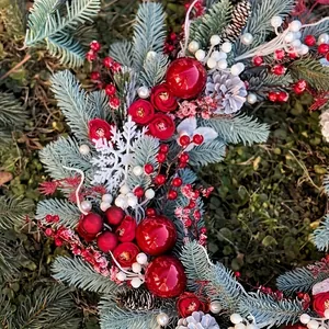 Festive Christmas wreath featuring pine needles, red roses, and ornaments for door decor.