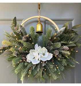 Close-up of a festive Christmas wreath with magnolia flowers, pine needles, and a gold bell.