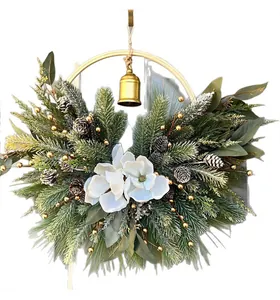 Detailed view of Christmas wreath featuring a gold bell, magnolia flowers, and pine needles.