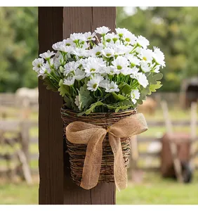 Detail of white daisy bouquet in a hanging wicker basket with burlap bow decor.
