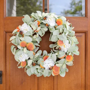 Corona de cosecha de otoño con hojas de oreja de cordero y flores en una puerta de madera