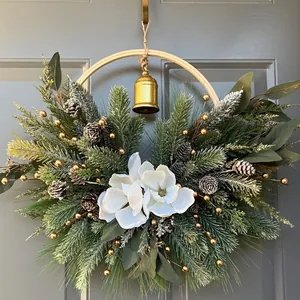 Christmas wreath with magnolia flowers, pine needles and a golden bell for door decor