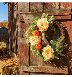 Detailansicht eines herbstlichen Erntekranzes mit Pfingstrosen und Kürbissen am Scheunentor