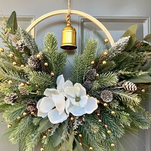 Festive Christmas door wreath featuring white magnolia flowers and a golden brass bell