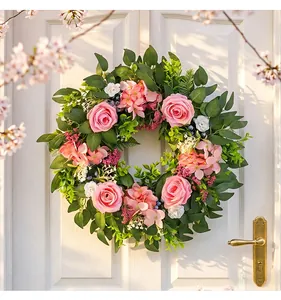 Detailed close-up view of an artificial pink rose wreath hanging on a white wooden door