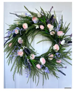 Detail view of a vibrant spring floral wreath with pink roses hanging on a white door