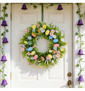 Beautiful colorful Easter egg wreath with spring flowers hanging on a white wooden front door
