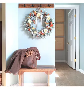 Rustic autumn acorn wreath decorated with sage leaves and silk ribbon in a home entryway.