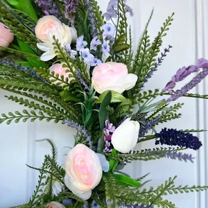 Macro detail of artificial spring wreath with pink roses and purple lavender sprigs.