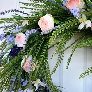Close-up detail of a vibrant spring flower wreath with pink ranunculus and lavender.