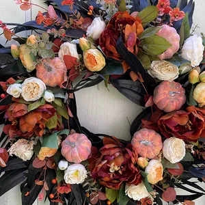 Elegant Halloween wreath decorated with black leaves, vibrant flowers and mini pumpkins