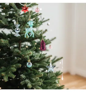 Primo piano di vari ornamenti natalizi lucidi appesi ai rami di un albero di Natale verde