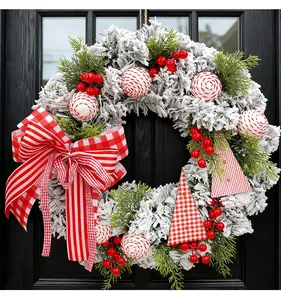 Nahaufnahme eines beflockten Weihnachtskranzes mit roten Beeren und Ornamenten