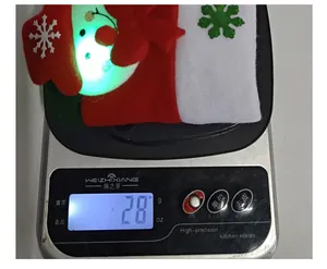 Mesure détaillée du poids d'un bonnet de Noël à LED rouge pesant environ 28 grammes
