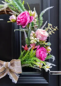 Detailed view of handmade artificial rose wreath with lace burlap bow on a black door