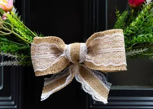 Detailed close-up of a rustic burlap bow with white lace on an artificial green wreath