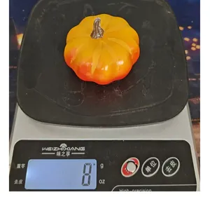 Detailopname van een kunstmatige schuimpompoen die 8 gram weegt op een weegschaal.
