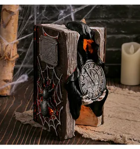 Dettaglio di un libro fantasma di Halloween in resina con effetto luce LED arancione.