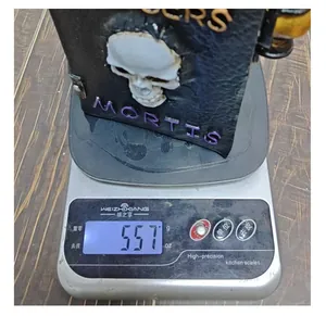 Detail view showing a Halloween resin skull book decoration weighing 557g on a scale