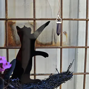 Detail of black acrylic cat reaching for purple crystal pendant on Halloween wreath