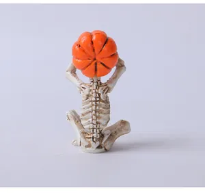 Vista posteriore di una statuina di scheletro in meditazione con testa di zucca arancio