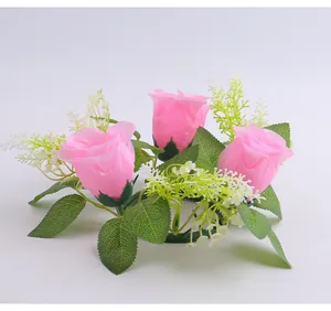 Detail view of pink artificial rose candle ring with green leaves for wedding decor
