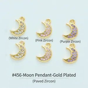 Dettaglio di ciondoli a luna placcati in oro con zirconi bianchi, rosa e viola.