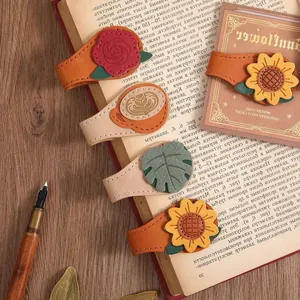 Dettaglio dei segnalibri magnetici in pelle con motivi di rose e girasoli su un libro.
