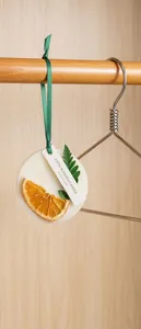 Gros plan d'une tablette de cire parfumée suspendue avec tranche d'orange séchée.