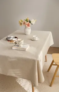 Detailed view of a beige linen-style rectangular tablecloth in a cozy warm dining room