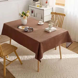 Textured brown linen-style tablecloth draped over a wooden table in a sunlit room