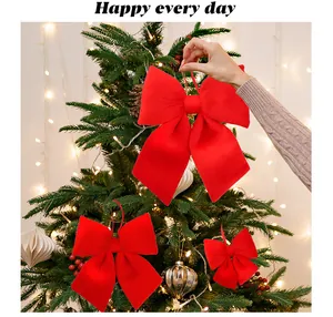 Grandi fiocchi di velluto rosso su un albero di Natale decorato con calde luci