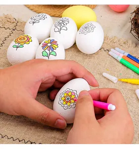Primer plano de manos pintando un huevo de Pascua DIY blanco con un rotulador rosa brillante.