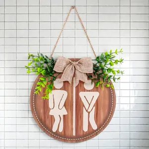 Humorous wooden round restroom sign with burlap bow and artificial greenery for farmhouse wall decor