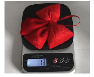 Dettaglio di un grande fiocco di velluto rosso che mostra il peso di 13g sulla bilancia