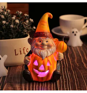 Dettaglio di uno gnomo di Halloween luminoso che tiene una zucca in resina decorativa