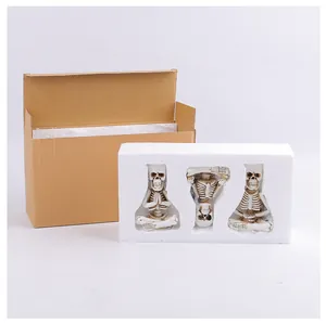 Detailed view of resin skeleton figurines inside protective foam and shipping box.
