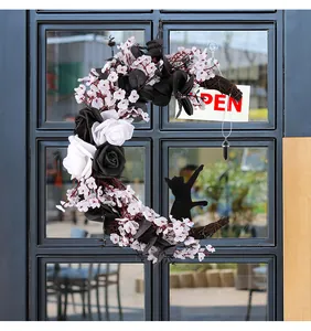 Detail of moon-shaped Halloween wreath with black roses and a cat silhouette on a door