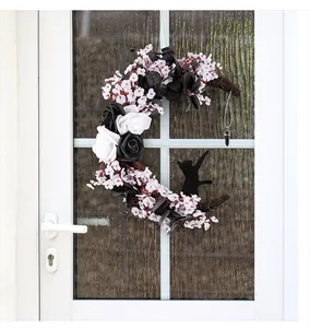 Halloween moon wreath with black roses and a cat silhouette hanging on a white door