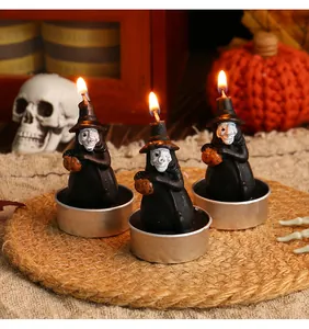 Detailed view of three lit Halloween witch-shaped tea light candles for party decor