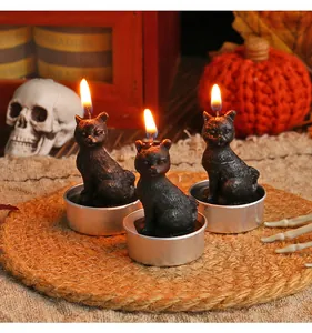 Detailed view of three lit black cat shaped candles for Halloween party decoration