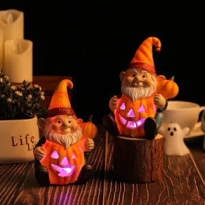 Coppia di gnomi di Halloween luminosi con zucche su un tavolo in legno rustico