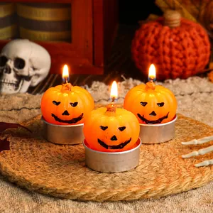 Lit Halloween pumpkin face tea light candles on a rustic woven mat for party decoration