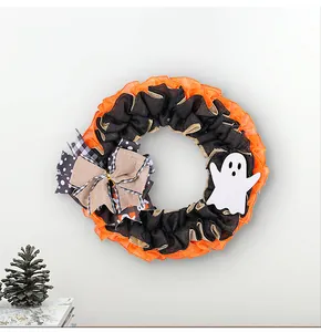 Detailed view of Halloween wreath featuring burlap bow and white ghost on orange mesh