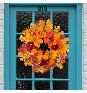 Close-up detail of a vibrant autumn maple leaf and sunflower wreath on a blue door